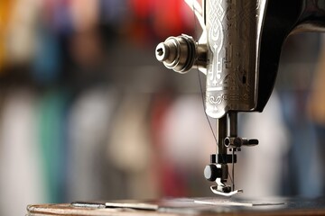 Canvas Print - Vintage sewing machine with thread on blurred background, macro view. Space for text