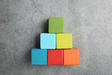 Canvas Print - Pyramid of colorful cubes on gray textured background, top view