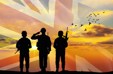 Silhouettes of soldiers with a background of the United Kingdom flag and a sunset or sunrise. Concept of national holidays. Commemoration Day.