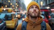 © Anna - The young man, wearing a warm yellow hat and a cozy sweater, gazes upward at the glowing city lights, surrounded by bustling traffic and urban architecture on a cloudy evening