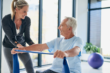 Fitness, old man and physiotherapist with band for stretching, rehabilitation and healing for injury. Wellness, senior patient and female person with help for physiotherapy, arms recovery or exercise