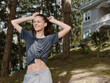 © SHOTPRIME STUDIO - Joyful young woman enjoying a sunny day outdoors, playfully stretching her arms while smiling broadly Relaxation and happiness in nature concept