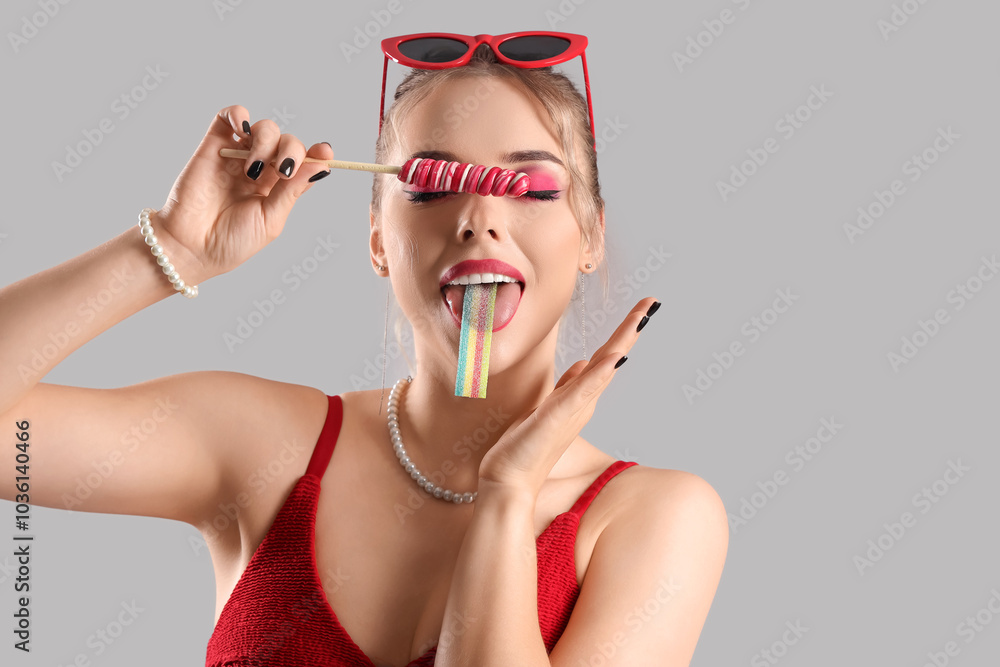 Young woman with candies on grey background, closeup