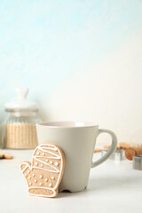 Tasty Christmas cookie and cup of drink on light background