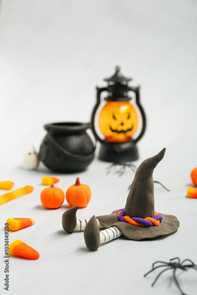 Halloween composition with witch doll, lantern and sweet candies on grey background