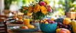 © GoDress - A table set for a summer meal with a variety of fresh fruits, a glass of juice, and a bouquet of colorful flowers.