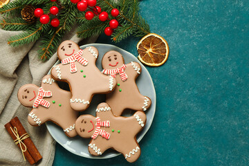 Plate with Christmas sweet gingerbread cookies and fir branches on green background