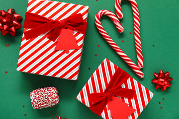 Composition with beautiful Christmas gifts, candy canes and decor on green background