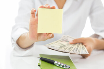 A person is holding a yellow blank note paper and a stack of money