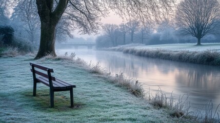 Leinwandbilder - A peaceful winter morning features a frosted wooden bench beside a calm river, surrounded by a misty landscape. Trees lined along the bank shimmer with frost as the early light casts a gentle glow.