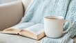 © NadenDesign - Cozy reading nook with a warm cup of tea and an open book on a soft knit blanket