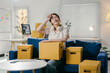 © PaeGAG - Young woman taking a break on the sofa and feeling exhausted after packing belongings in cardboard boxes, preparing for relocation