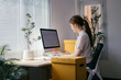 © PaeGAG - Young entrepreneur is working on her computer while sitting at her desk, managing her online business.  She has a calendar open on her computer screen and boxes next to her