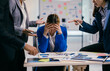 © PaeGAG - Businesswoman is feeling stressed while her coworkers are being aggressive and blaming her for something during a business meeting