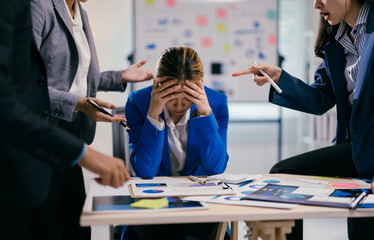 businesswoman is feeling stressed while her coworkers are being aggressive and blaming her for somet