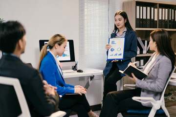 Diverse asian business team brainstorming in a modern office, discussing strategies for success with laptops and charts