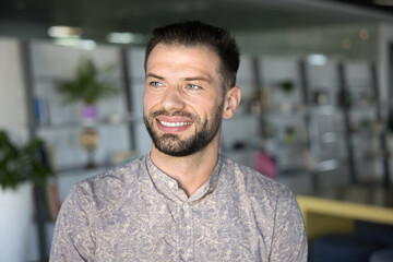 Cheerful attractive young entrepreneur guy looking away with toothy smile, thinking on business success, successful startup. Happy businessman in casual, creative specialist casual portrait