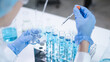 © Supapich - Close-up hands dropping fluid from dropper flask beaker into blue test tube sample laboratory for compare in medicine chemical biology medical science experiment technology biotechnology analysis