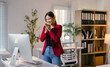 © Parichat - Smiling businesswoman is standing in her office, clapping her hands in front of her computer during a work video call