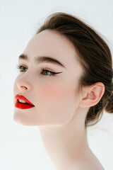 Close-up portrait of a beautiful woman with glamorous makeup and a fresh hairstyle, showcasing her elegant features and radiant skin in a natural studio setting