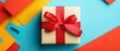 © santima - Gift box with red ribbon on colorful background