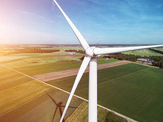 aerial view of a single wind turbine standing tall amidst expansive agricultural fields under a clear blue sky