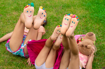 Poster - Children's feet painted on the grass. Selective focus.