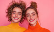 © Vlad - Vibrant Portrait of Two Smiling Women in Bright Turtleneck Sweaters Against Pink Background