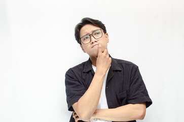 Thoughtful asian man thinking and wondering with hand touching skin as thinking gesture isolated over white background. asian man with glasses and black and white casual shirt feeling uncertain.