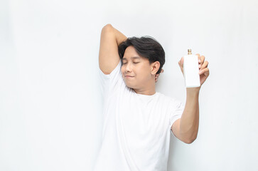 young clean and fresh asian man in white t-shirt using perfume. freshness concept of man spraying perfume. mock up bottle of perfume.