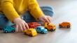 © Pointofview - A child is playing with a collection of toy cars on a wooden floor