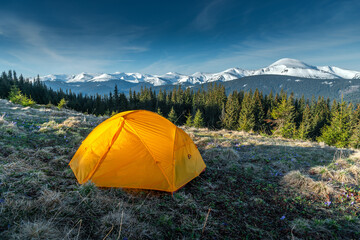 tent on foreground in the mountains, first morning light. campsite with a yellow dome tent on a high