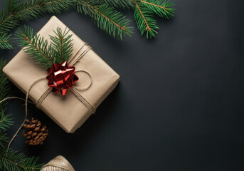 A beautifully wrapped gift adorned with a red bow and pine sprigs, set on a dark background, perfect for the holiday season