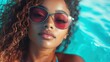© Maximages  - A relaxing scene of a woman with curly hair enjoying the poolside ambiance, wearing stylish sunglasses that reflect a carefree and serene summer vibe.