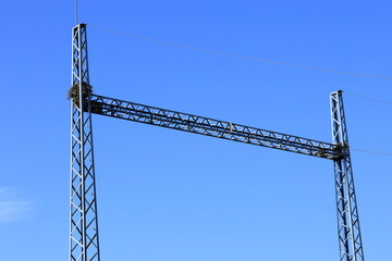 Metal tower. Part of power supply. Old bird nest. Blue sky.