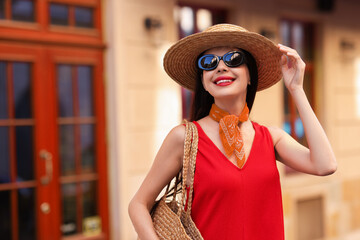 Sticker - Smiling young woman in stylish hat and sunglasses on city street