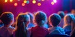 © kiimoshi - Children watching a colorful stage performance with vibrant lighting.