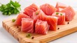 © Autaporn - Fresh salmon cubes on a wooden board, garnished with green onions and parsley, ready for cooking or sushi preparation.