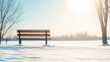 © Bonsales - Snow-covered bench on a sunny winter morning with a bright sun in the background