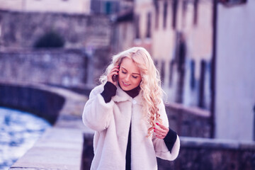 Smiling tourist woman talking on the phone walking near a canal