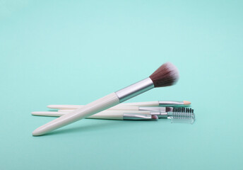 Makeup brushes floating on mint green background