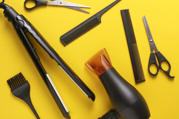 Flat lay hairdressing tools and accessories for hair styling on yellow background. Top view