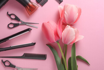 Flat lay hairdressing tools and accessories for hair styling with tulips on pink background. Top view.