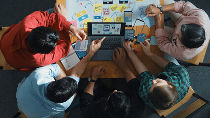 Top view of project manager using laptop working on Ux Ui design for mobile phone interface while marketing team designing software program by using brainstorming mind map. Top view. Convocation.