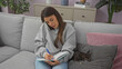© Krakenimages.com - A young woman multitasks, talking on the phone while writing notes, with her chihuahua beside her on the couch in a cozy living room.