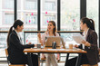 © kenchiro168 - Collaborative business meeting with three women discussing ideas around table, showcasing teamwork and engagement in modern office space