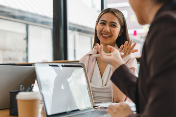 woman is engaged in lively conversation with colleague in modern office setting, showcasing friendly and professional atmosphere. Her smile reflects enthusiasm and openness