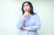 © M Alfan Setyawan - beautiful pensive asian woman daydreaming looking away woth thumbs up kiss by lips with arm folded wear formal suit isolated by white background