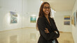 © Krakenimages.com - Young woman smiling indoors in an art gallery wearing glasses and a black blazer with arms crossed