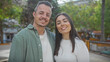 © Krakenimages.com - A happy couple embracing in a park with trees in a city setting, showcasing love and togetherness.